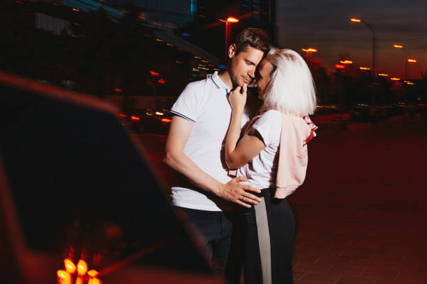 젊은 행복한 부부는 밤 도시 거리에서 키스하는 사랑에 빠졌습니다. 플래시 효과와 사진 - romantic scene flash 뉴스 사진 이미지