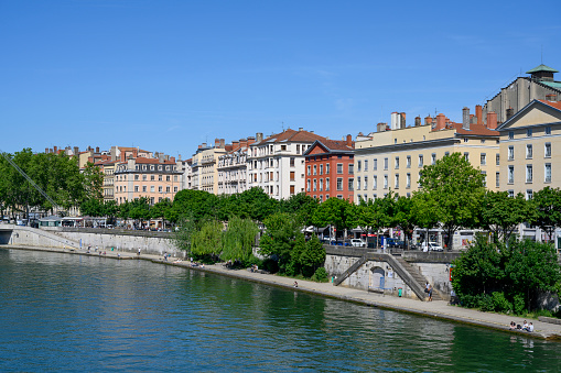 View along the Rhone river in central Lyon, France, a sunny summer day. Next to the river residential buildings are showing.