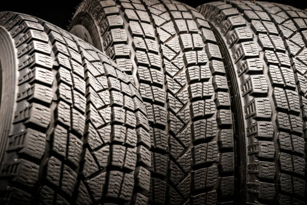 istock three old used winter tires. Close-up on a black background. 1165865995