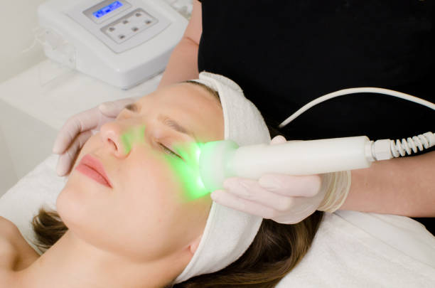 beautician doing green led light therapy to female customer in beauty salon, facial photo therapy for skin pore cleansing beautician doing green led light therapy to female customer in beauty salon, facial photo therapy for skin pore cleansing. Anti-aging treatments and photo rejuvenation procedure light therapy stock pictures, royalty-free photos & images