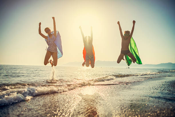 istock Kids superheroes jumping on the beach 1165875256