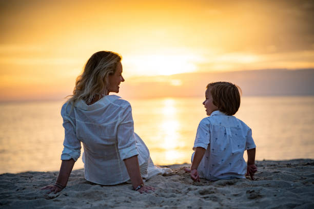 istock Rear view mother and son enjoying at beach on sunset 1165876401