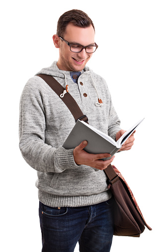 Smiling  handsome male student with glasses and a shoulder bag holding a book, isolated on white background.