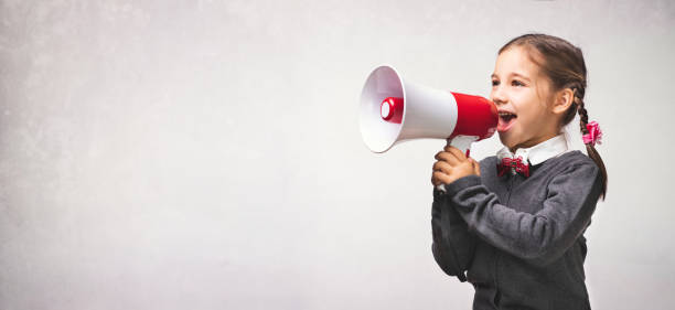 istock Child Girl Student Shouting Through Megaphone on Grey Backdrop with Available Copy Space. Back to School Concept. 1165877571