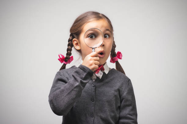 istock Child Girl Student Looking Through Magnifying Glass on Grey Background with Available Copy Space. Back to School Concept. 1165878191