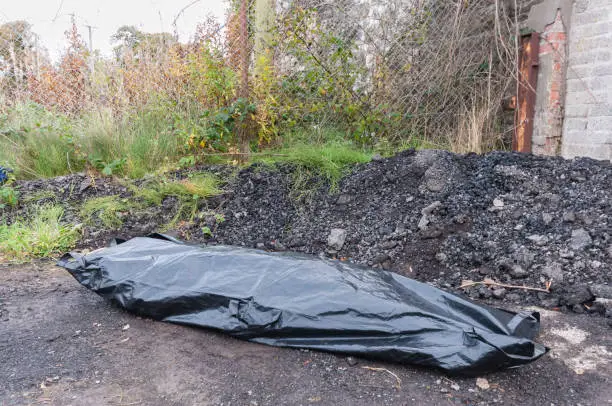 A body inside a body bag at an isolated location.