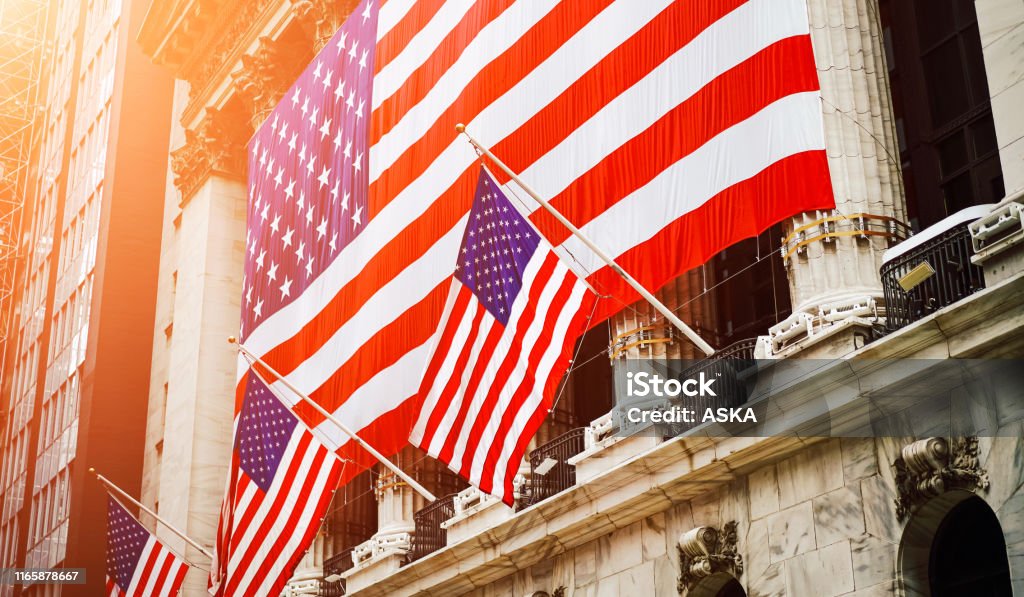 Wall Street, USA Wall street sign in New York with American flags New York Stock Exchange Stock Photo