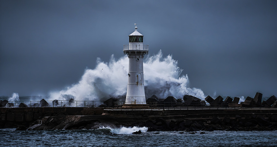 Wollongong Harbour, NSW, Australia - June 4: Wave breaking in a circular way behind the Breakwater Lighthouse of Wollongong during a storm, 16:9 aspect ratio