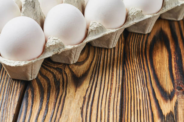 istock Set of chicken eggs in cardboard box lies on rustic wooden table. Space for text 1165885356