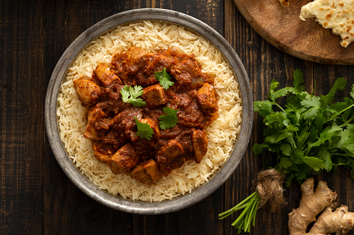 Indian Food - Bowl of chicken vindaloo curry over basmati rice and naan bread.