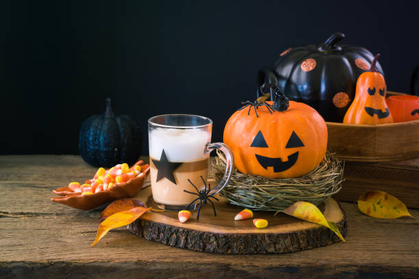 istock Halloween holiday concept with latte macchiato cup, candy corn  and pumpkin decoration on wooden table 1165890760