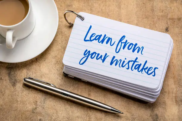 Learn form your mistakes - reminder on a stack of  index cards with a cup of coffee