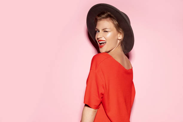 chica sonriente en sombrero de moda y vestido rojo - pink hat fotografías e imágenes de stock