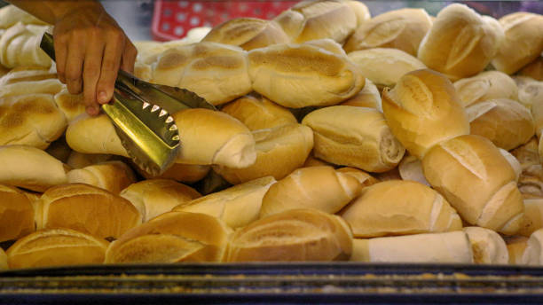 um recipiente grande do pão com uma mão que prende um espátula ao agarrar um pão - french loaf - fotografias e filmes do acervo