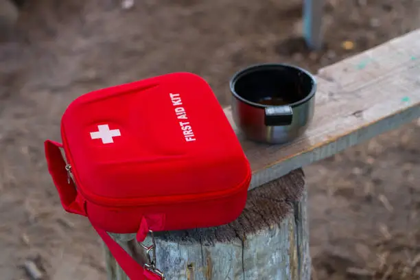 red first aid kit case on wooden bench