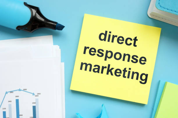 istock Writing note showing direct response marketing. The text is written on a small colored paper. Graphs on the paper sheet, markers, wooden background are on the photo. 1165896143