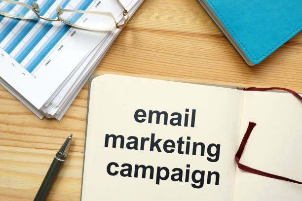 istock Writing note showing email marketing campaign. The text is written in the notebook. Graphs on the paper sheet, pen, wooden background are on the photo. 1165896247