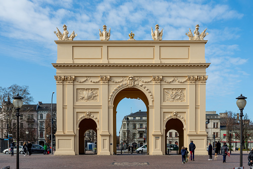 Potsdam, Brandenburg/Germany - 24.03.2019: The Brandenburg Gate in Posdam on a sunny day with some clouds. You see a street scene