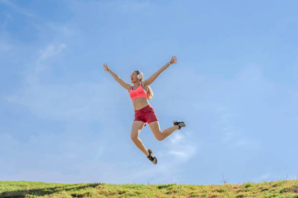 istock Joyful sportive lady jumping up on green hill 1165904547