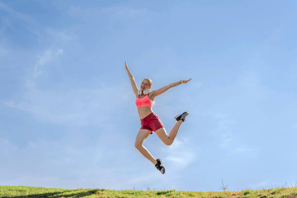 istock Happy sportive lady jumping up on green hill 1165904598