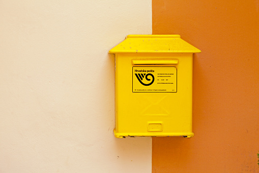 Zadar, Croatia - April 14 2019: Yellow Croatian public mailbox on a wall of the city center.