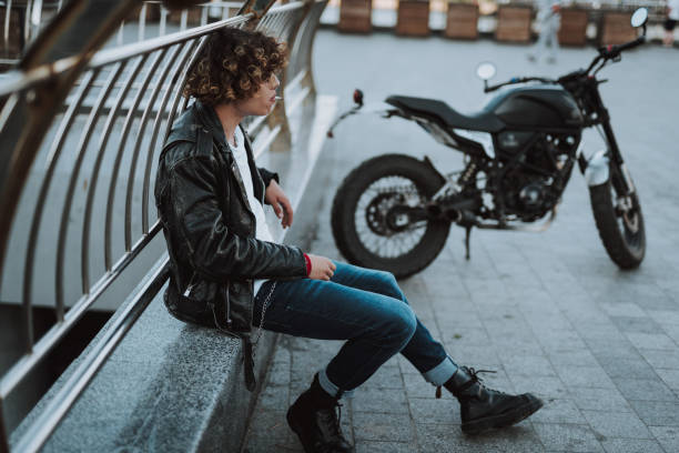 istock Curly young biker smoking at the banister 1165908170