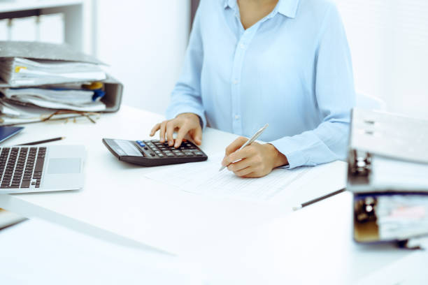 istock Unknown female bookkeeper or financial inspector calculating or checking balance, making report, close-up. Internal Revenue Service at work with financial document. Tax and audit concept 1165909513