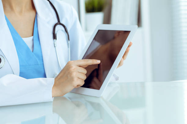 istock Female doctor using tablet computer while sitting at the workplace, close-up of hands. Medicine, healthcare and help concept 1165910045