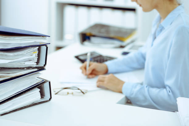 istock Unknown female bookkeeper or financial inspector calculating or checking balance, making report, close-up. Internal Revenue Service at work with financial document. Tax and audit concept 1165910584