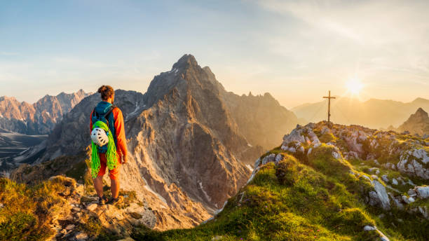 montanhista de montanha na cruz da cimeira com opinião da glória à parede do leste de watzmann, parque nacional de berchtesgaden - alpenglow sunrise sun scenics - fotografias e filmes do acervo