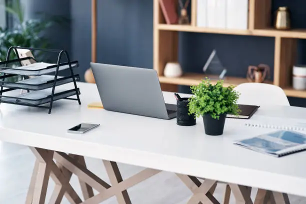 Shot of a laptop and other various items on a work desk in a modern office