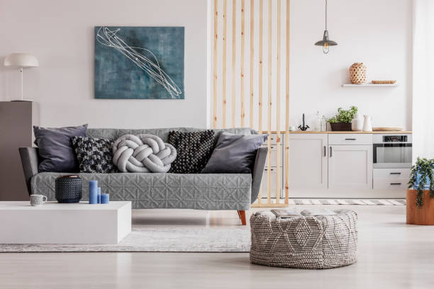 istock Open plan living room and kitchen interior with white cupboards and grey sofa with pillows 1165916773
