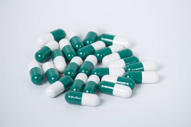 istock Green pills an pill bottle on white background 1165917521