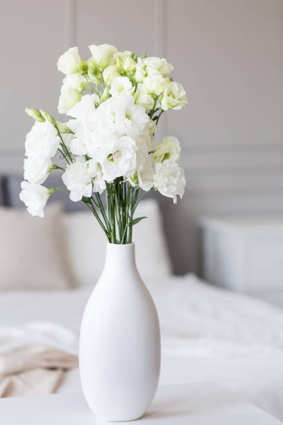 istock White flowers in vase in elegant grey bedroom interior with simple bedding 1165922518