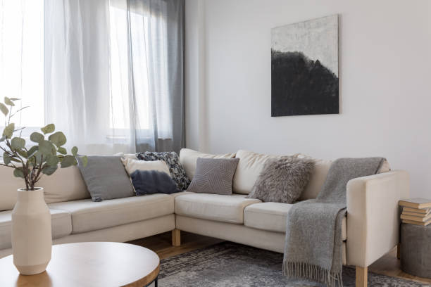 istock Beige comfortable corner sofa with grey pillows in elegant living room interior with white wall 1165922836