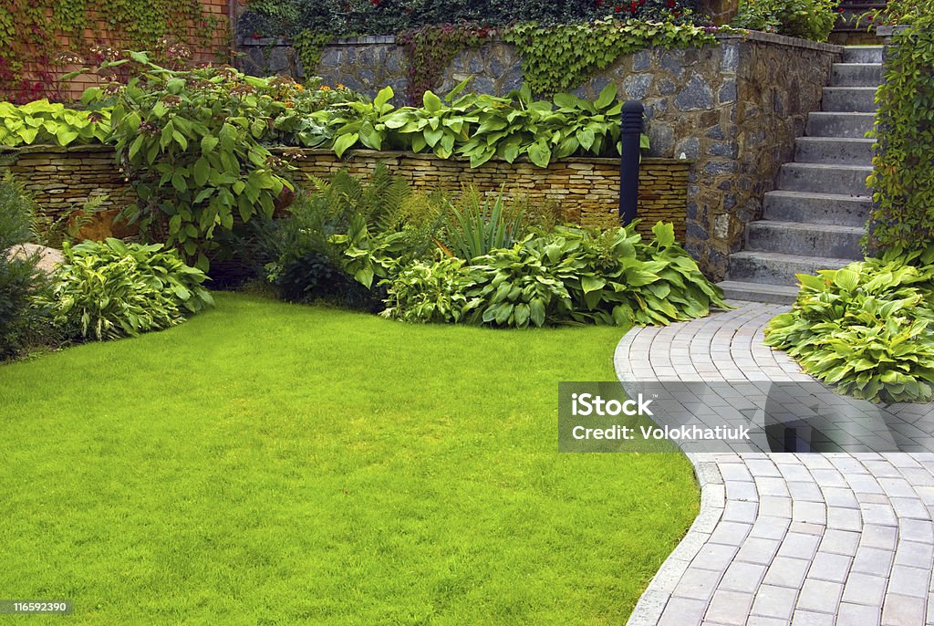 Garden Garden stone path with grass growing up between the stones Alley Stock Photo