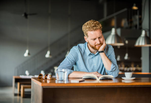 istock Young man reading a book in a coffee shop. 1165926029