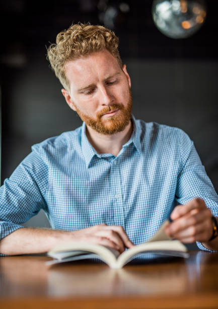 istock Dedicated young man reading a book in a coffee shop. 1165926064