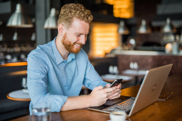 istock Happy young man texting a message while working in a coffee shop. 1165926160