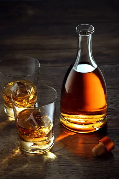 view of glasses of  whiskey and a bottle aside on color wooden  background.