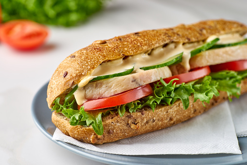 Big sandwich with chicken and vegetables on dish. Fastfood concept