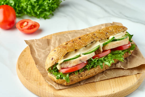 istock Big sandwich with chicken and vegetables on wooden board 1165929344