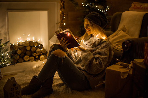 Young woman reading book on the christmas eve