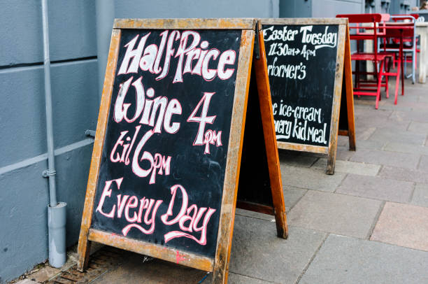 istock Blackboard A-boards outside a pub cafe advertising half price wine between 4pm and 6pm every day. 1165938723