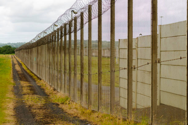 istock Outer fence of a high security prison topped with razor wire 1165938860