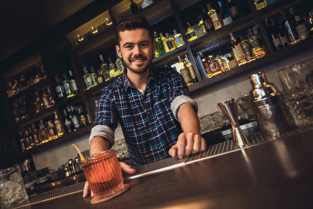 istock Young bartender standing at bar counter serving cocktail cheerful 1165956563