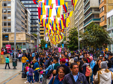 A lot of people in the street with colombian flags, Bogota Colombia August 3/2019. People in the downtown of Bogota Colombia enjoying street artists and buying things. Colombian flags as ornaments.