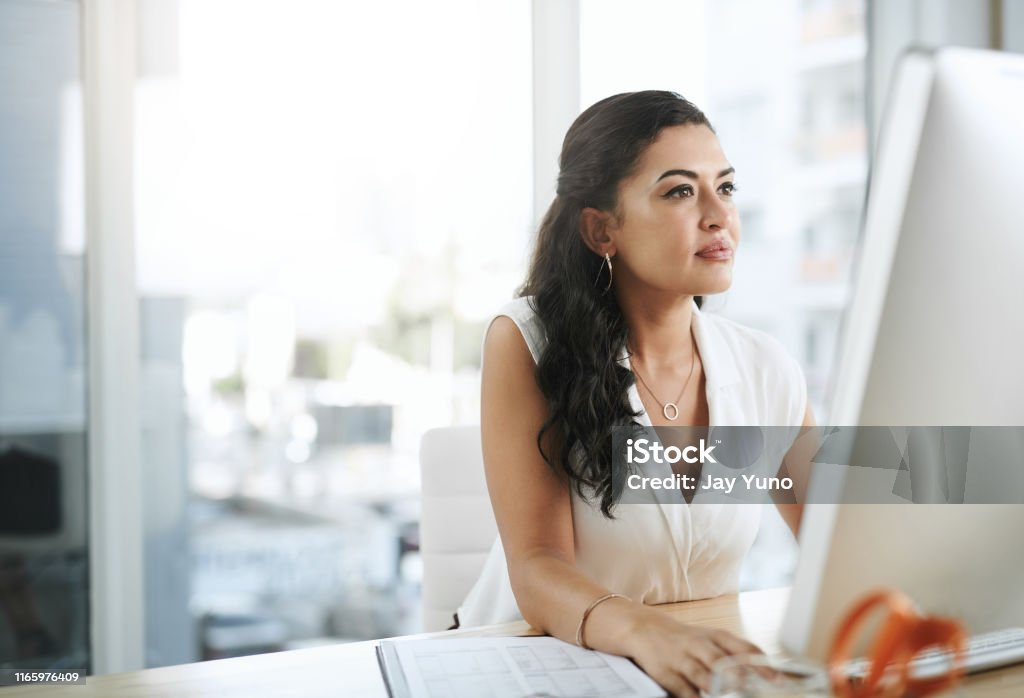 Productivity is born from focus Shot of a young businesswoman using a computer at her desk in a modern office Office Stock Photo
