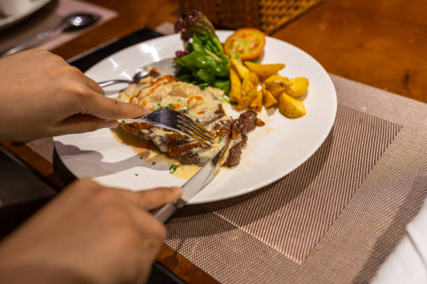 istock Human hand cutting delicious sirloin steak on white plate 1165976468