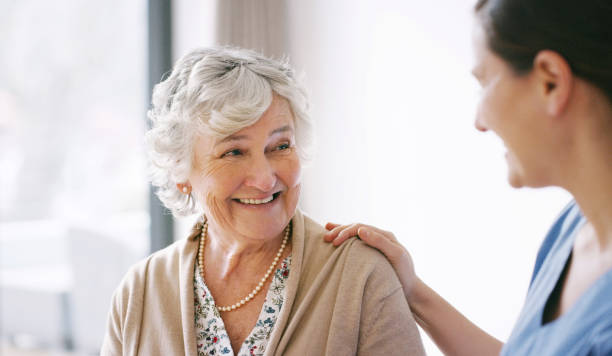 Just knowing you're here makes me happy Shot of a happy senior woman being cared for by a young nurse in a retirement home hand on shoulder photos stock pictures, royalty-free photos & images